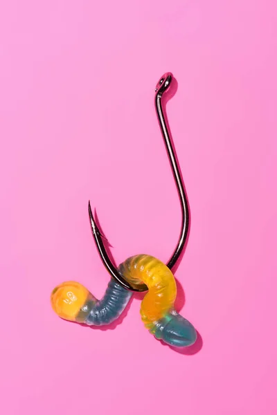 Colorful gummy worm on fishing hook on pink — Stock Photo