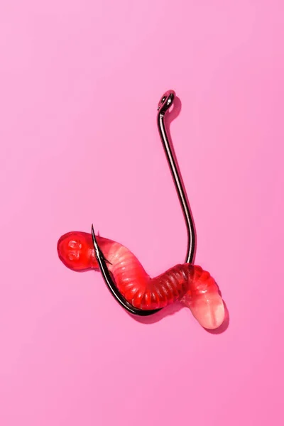 Roter Gummiwurm am Angelhaken auf rosa — Stockfoto