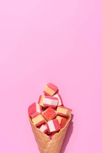 Vue de dessus des bonbons sucrés gommeux en cône de gaufre sur rose — Photo de stock