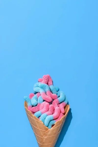 Vista superior de gusanos gomosos dulces en cono de gofre en azul - foto de stock