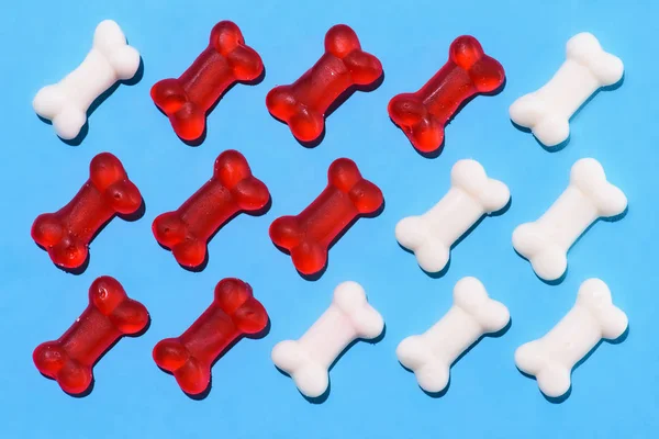 Top view of gummy candies in shape of red and white bones composition on blue — Stock Photo