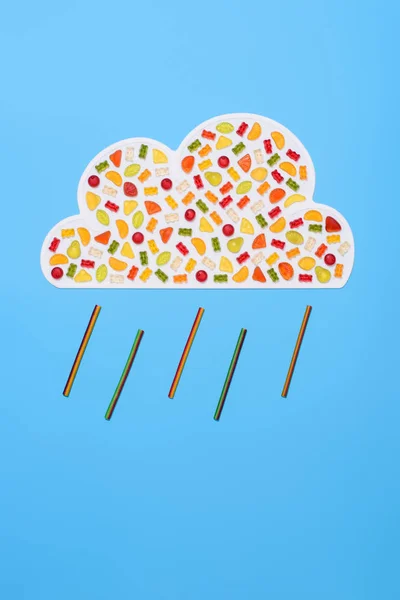 Сверху вид дождливого облака из мармеладных конфет, изолированных на голубом — стоковое фото