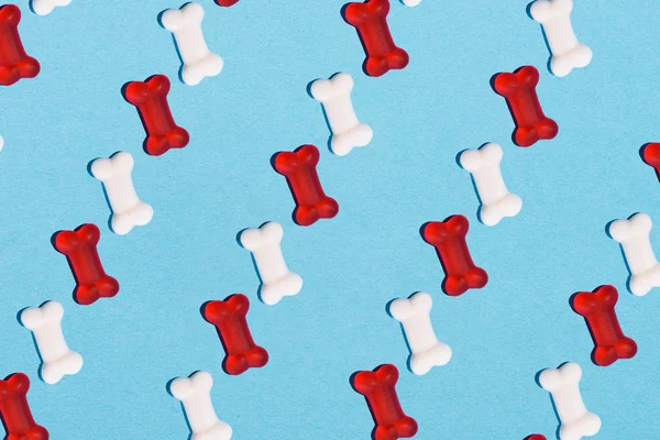 Top view of gummy candies in shape of bones in rows on blue — Stock Photo