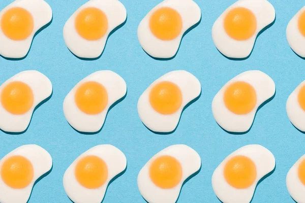 Вид зверху смачні жувальні цукерки у формі смажених яєць на синьому — стокове фото