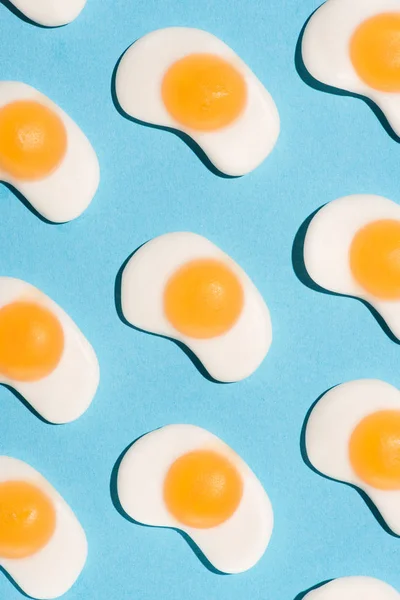 Вид зверху солодких жувальних цукерок у формі смажених яєць на синьому — стокове фото