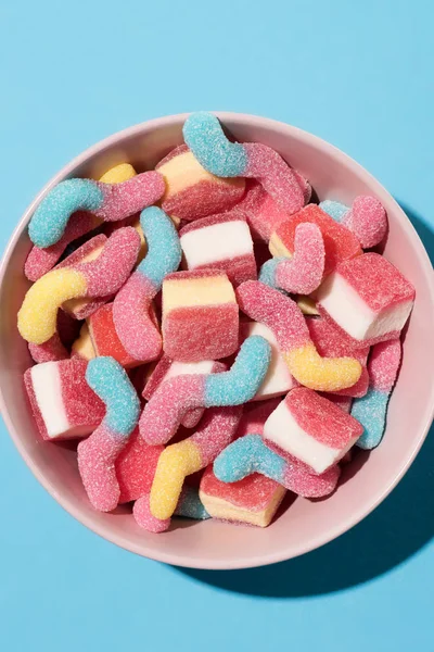 Top view of colorful gummy candies in bowl on blue — Stock Photo