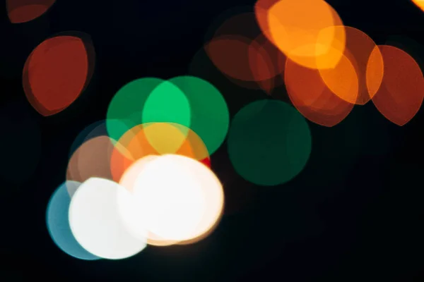 Vue rapprochée de lumières bokeh colorées sur fond sombre — Photo de stock