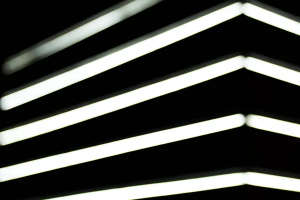 Vista de cerca de las lámparas de rayos blancos borrosas sobre fondo negro - foto de stock