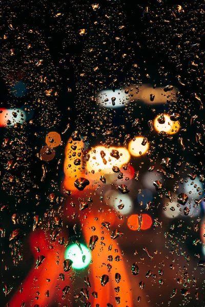 Vista da vicino delle gocce di pioggia sulla finestra e le luci della città bokeh sullo sfondo — Foto stock
