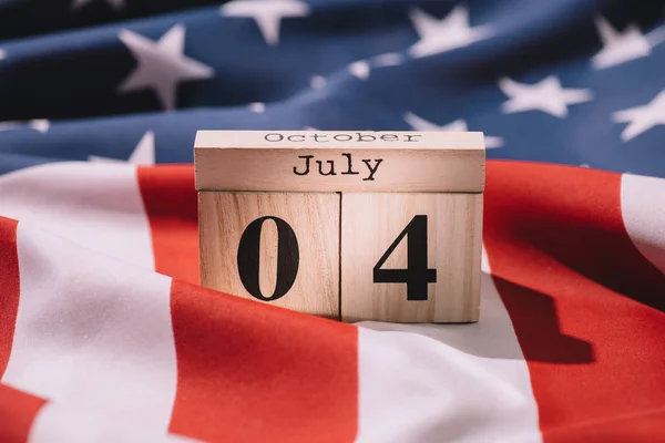 Close up view of wooden calendar with 4th july date on american flag, americas independence day concept — Stock Photo
