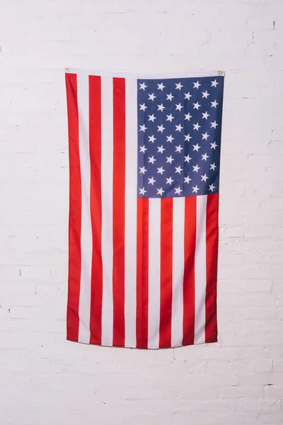 Close up view of american flag hanging on white brick wall — Stock Photo