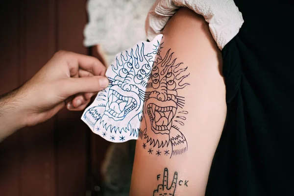 Recortado tiro de tatuaje artista transferir boceto de tatuaje en el hombro en salón de tatuaje - foto de stock