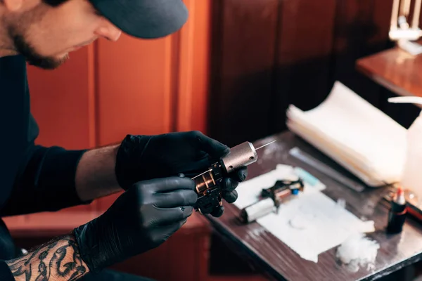 Selective focus of tattoo artist in gloves with tattooing machine in salon — Stock Photo