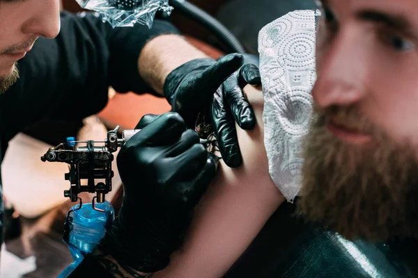 Cropped shot of tattooing process of tattoo on shoulder in salon — Stock Photo