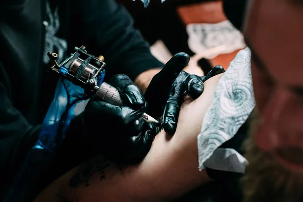 Cropped shot of tattooing process of tattoo on shoulder in salon — Stock Photo