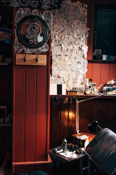 Close up view of sketches on wall, arranged tattoo machines and paint at tattoo salon — Stock Photo