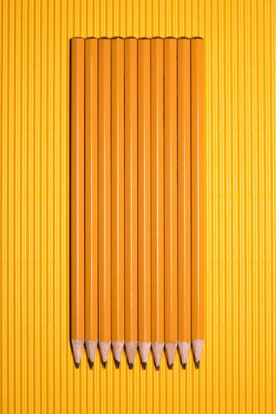 Top view of arranged graphite pencils placed in row on yellow — Stock Photo