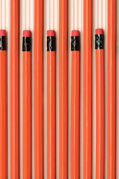 Vista superior de lápis de grafite vermelho com borrachas colocadas em linha no bege — Fotografia de Stock