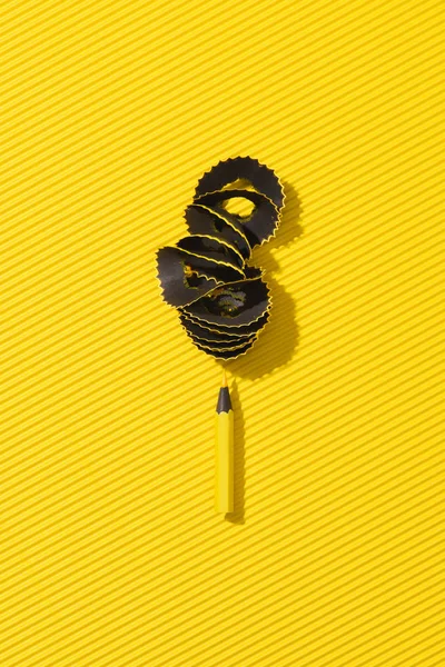 Вид зверху на стружку олівця і жовтий графітовий олівець на жовтому — стокове фото