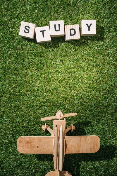 Верхний вид деревянной игрушечной плоскости и надпись из блоков на зеленой траве — стоковое фото