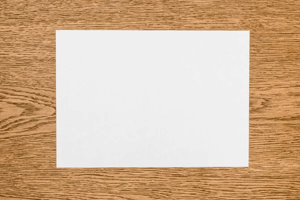 Vista elevada del papel blanco vacío en la mesa de madera - foto de stock