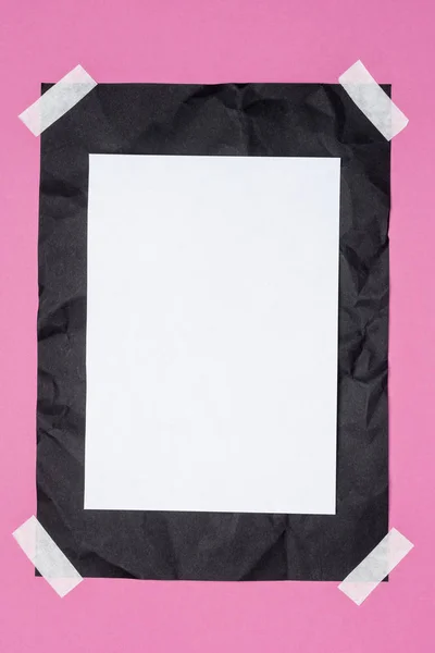 Vista superior del papel blanco vacío sobre papel arrugado negro sobre rosa - foto de stock