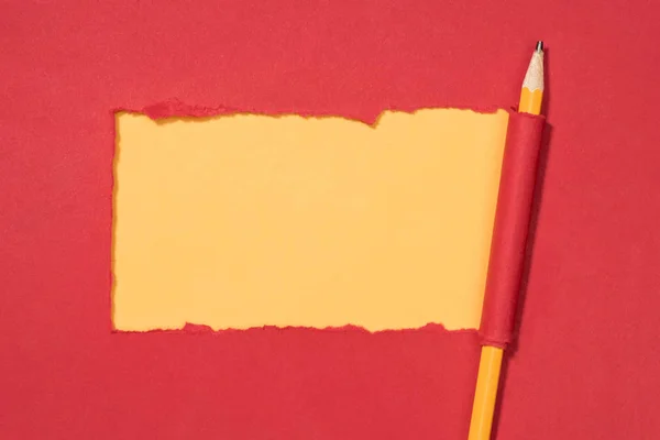 Draufsicht auf zerrissenes rotes Papier und eingewickelten Bleistift auf gelb — Stockfoto