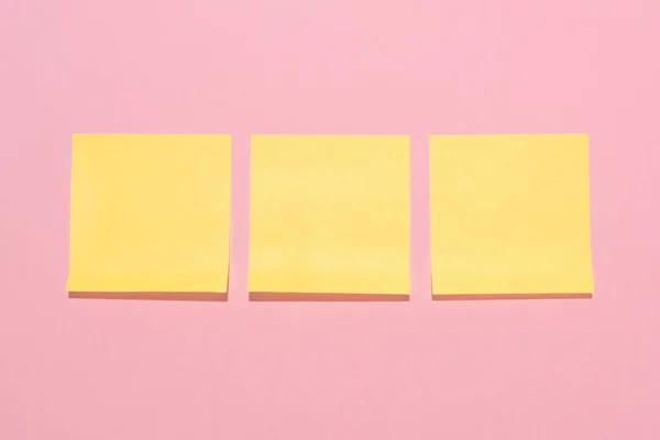 Top view of blank yellow stick it notes placed in row on pink — Stock Photo