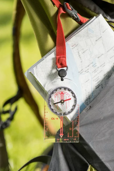 Close-up view of compass hanging on backpack and map — Stock Photo