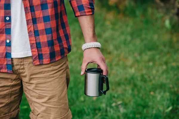 Vista parcial del hombre en camisa a cuadros sosteniendo taza al aire libre - foto de stock