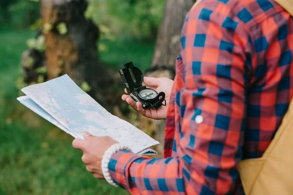 Plan recadré d'un jeune voyageur tenant une boussole et une carte en forêt — Photo de stock