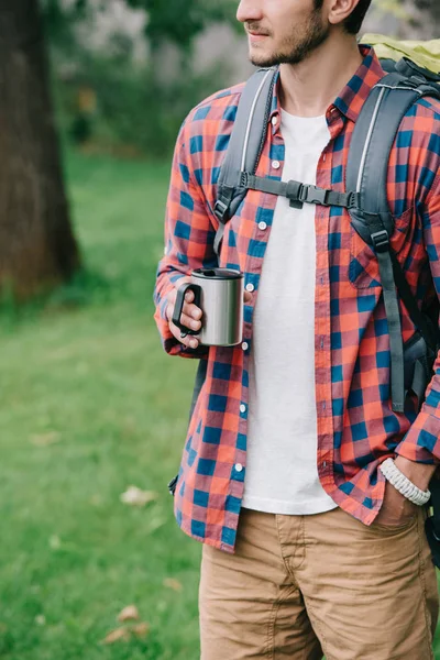 Cropped shot of young man with backpack holding mug — Stock Photo