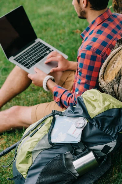 Colpo ritagliato di giovane viaggiatore maschile utilizzando computer portatile su erba — Foto stock