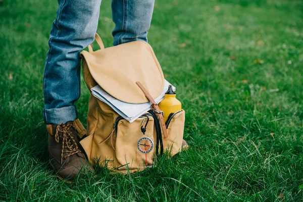 Tiro cortado de homem de pé na grama verde com mochila — Fotografia de Stock