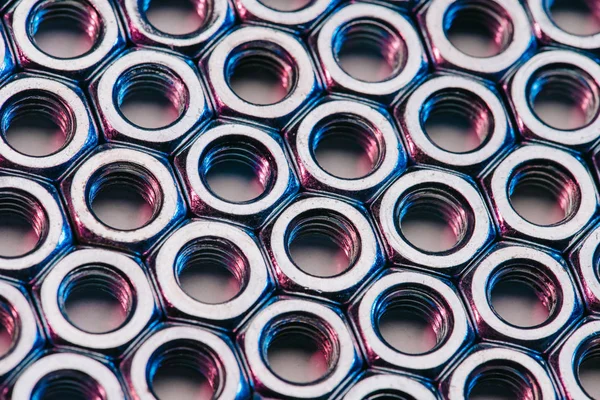 Set of screw nuts with pink reflection — Stock Photo