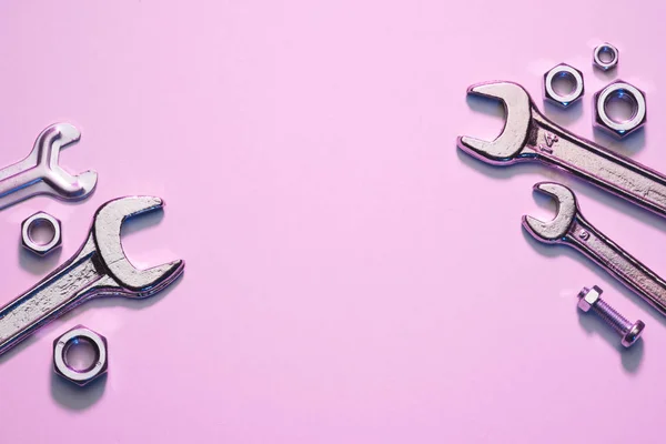Верхний вид ключей, гаек и винтов на розовой поверхности — стоковое фото