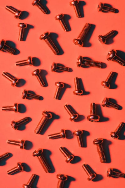 Set of small metal screws on red — Stock Photo