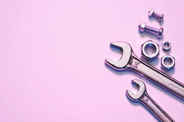 Вид зверху на гайкові ключі, гайки і гвинти на рожевій поверхні — стокове фото
