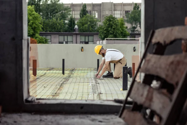 Selective focus of builder in protective googles and hardhat working at construction site — Stock Photo