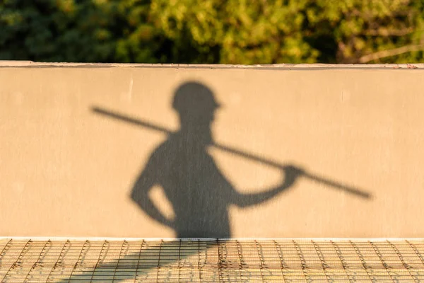 Sombra del constructor en el casco de protección que lleva la estructura metálica en el sitio de construcción — Stock Photo