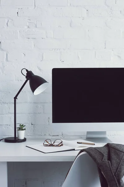 Computer and glasses on notebook on table in modern office — Stock Photo