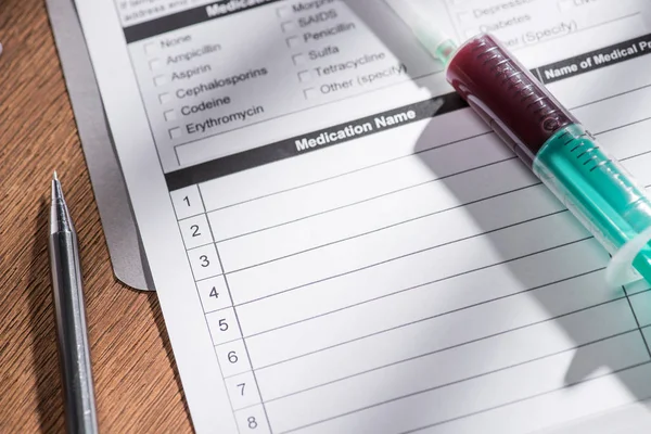 Selective focus of medical questionary and syringe with blood sample on table, world hepatitis day concept — Stock Photo