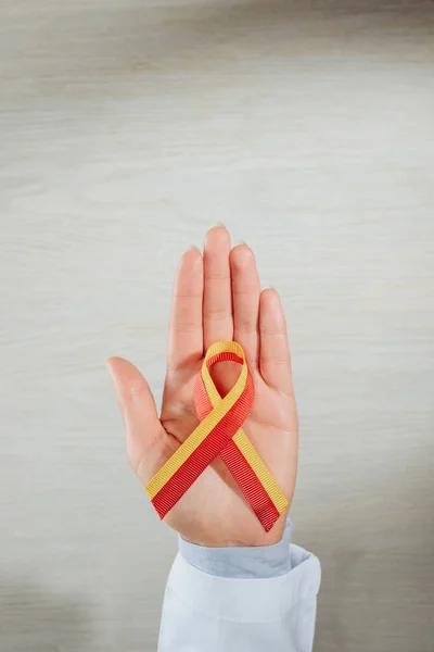 Cropped image of female doctor holding ribbon over table, world hepatitis day concept — Stock Photo
