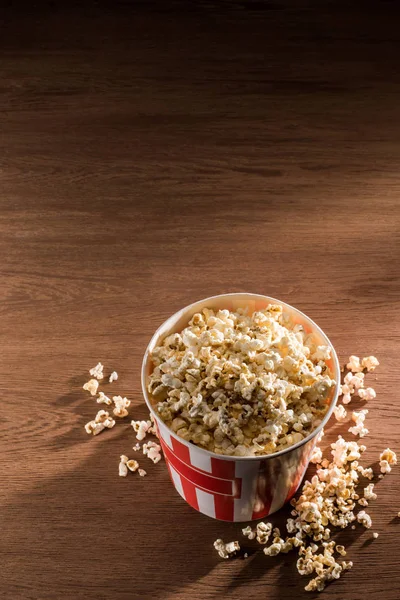 Nahaufnahme eines Einwegeimers mit Popcorn auf einer hölzernen Tischplatte — Stockfoto