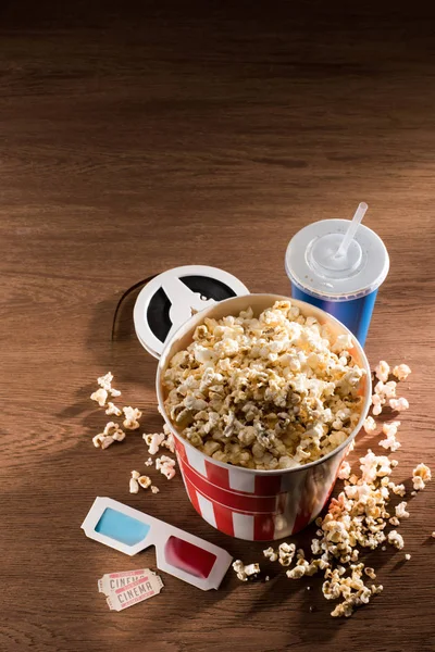 Close up view of paper bucket with popcorn, soda drink, 3d glasses and retor cinema tickets on wooden tabletop — Stock Photo