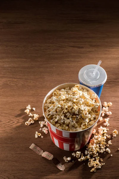 Close up view of paper bucket with popcorn, soda drink and retro cinema tickets on wooden tabletop — Stock Photo