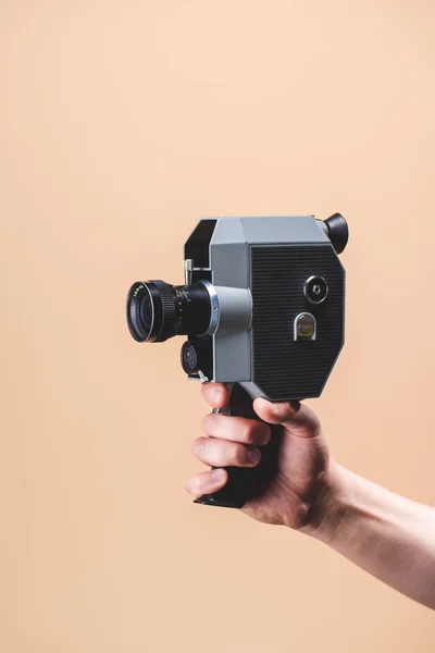 Cropped shot of man holding retro camera in hand isolated on beige — Stock Photo