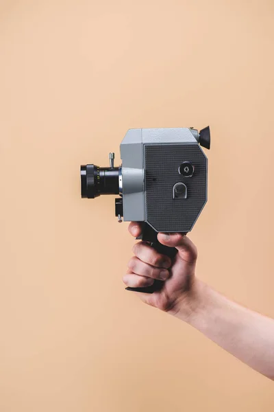 Cropped shot of man holding retro camera in hand isolated on beige — Stock Photo