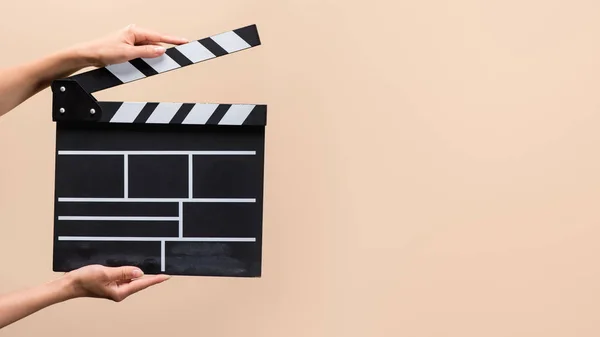 Partial view of woman holding clapper board in hands isolated on beige — Stock Photo