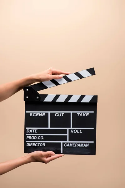 Partial view of woman holding clapper board in hands isolated on beige — Stock Photo